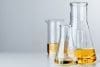 Laboratory Glassware With Yellow Oily Liquid On Grey Background