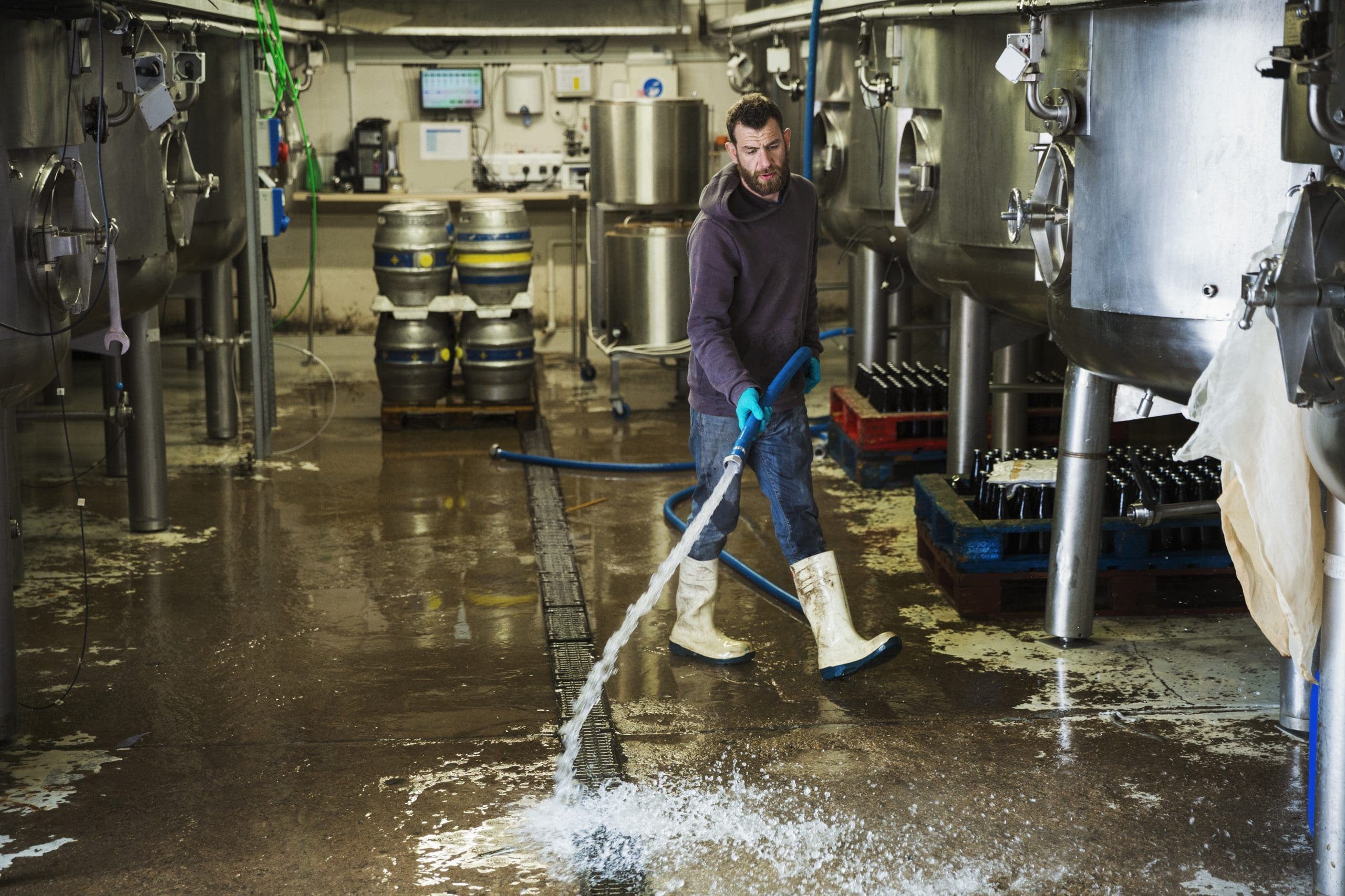 Man Working In A Brewery, Cleaning Floor With Water Hose.,renegade Brewery,england