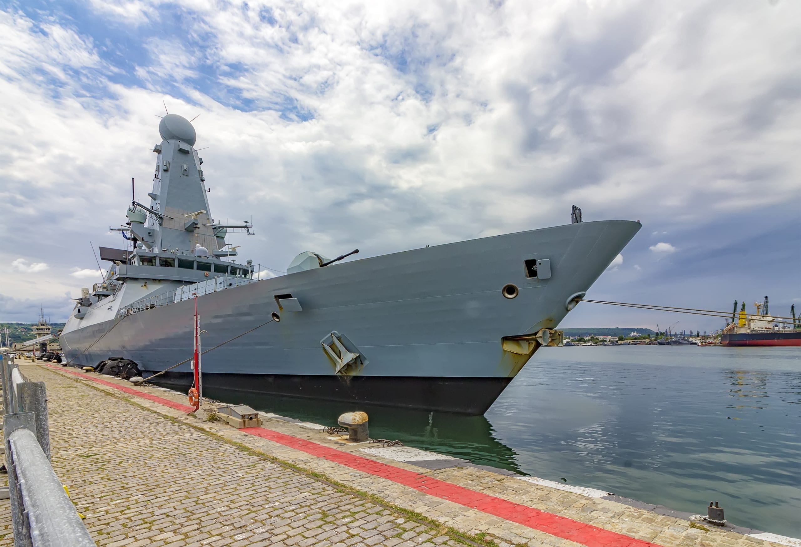Military Navy Ship In Port. Military Sea Landscape With Cloudy Sky At Sunset