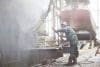 Worker Using High Pressure Hose On Boat In Shipyard Workshop
