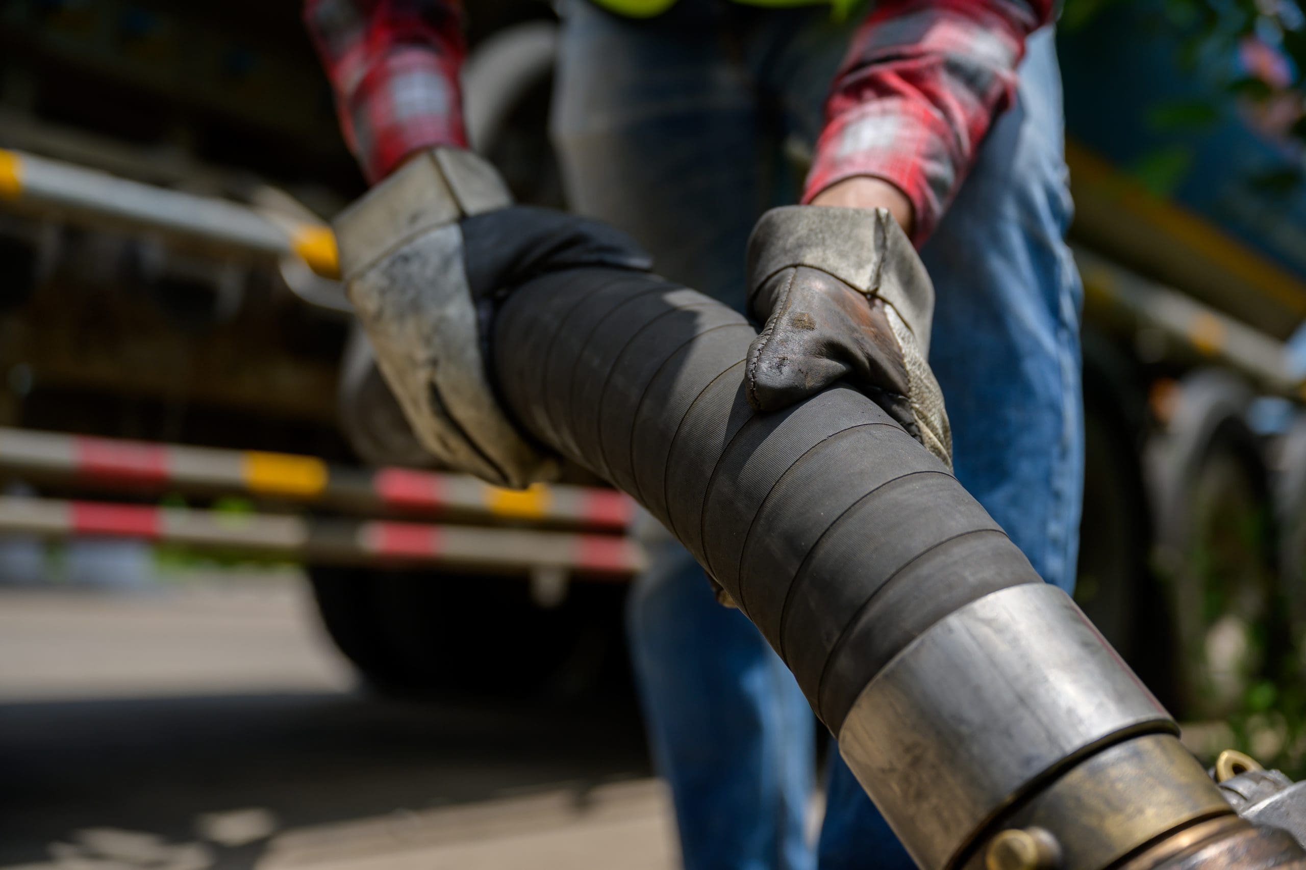A Close Up Of A Worker Attaching An Industrial Fuel Hose While Wearing Heavy Duty Gloves Emphasizes How Crucial Precision And Safety Are To Both Industrial And Transportation Fuel Transfer Operations.